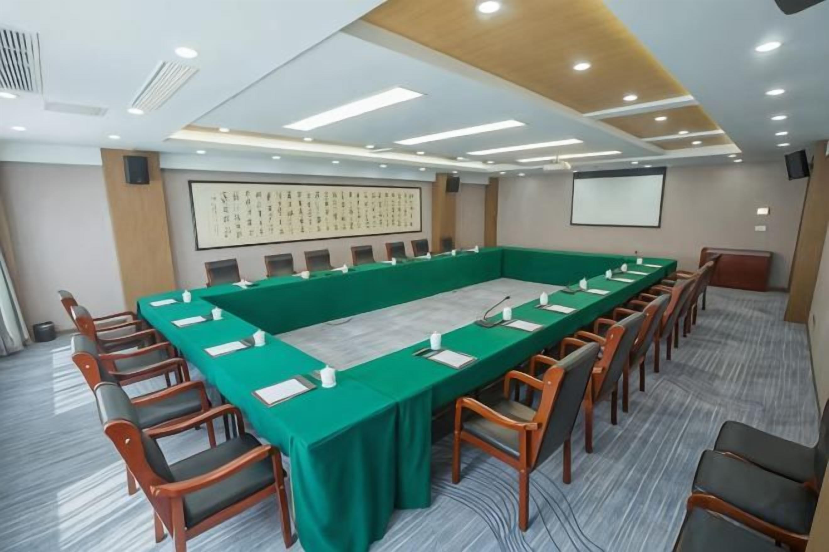 A conference room with a long table, chairs, a projector screen, and a whiteboard.