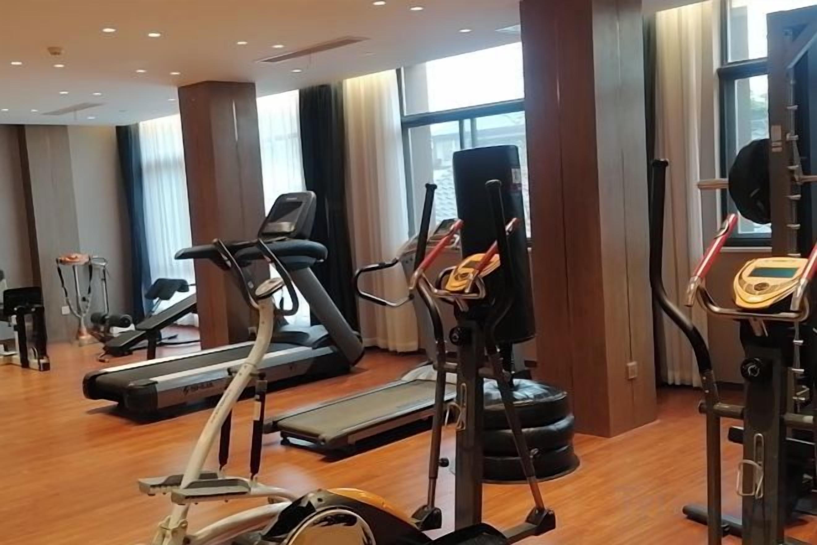A gym with cardio machines, weightlifting equipment, and a treadmill.