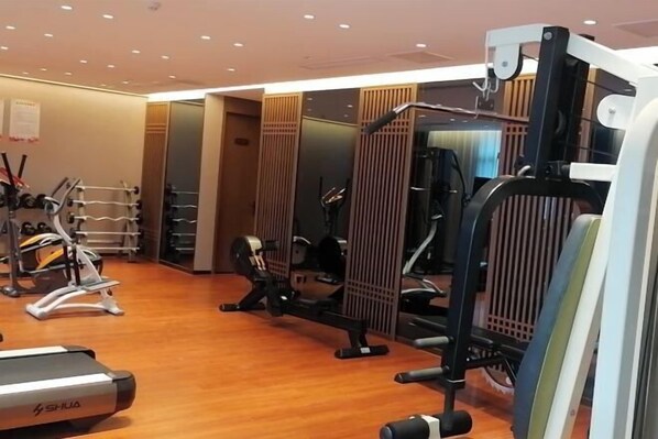 A gym with exercise equipment, wooden flooring, and a mirrored wall.