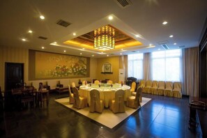 A conference room with a round table, chairs, a chandelier, and a painting on the wall. - Zaolin Mountain Villa (Yizheng)