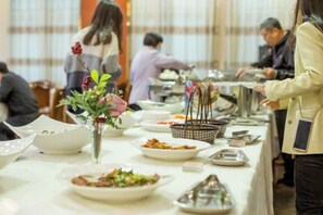Ein reichhaltiges Buffet mit verschiedenen Speisen und einer Blumenvase auf einem Tisch.