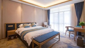 Ein modernes Hotelzimmer mit einem großen Bett, Nachttischen, einem Schreibtisch und einem Stuhl.