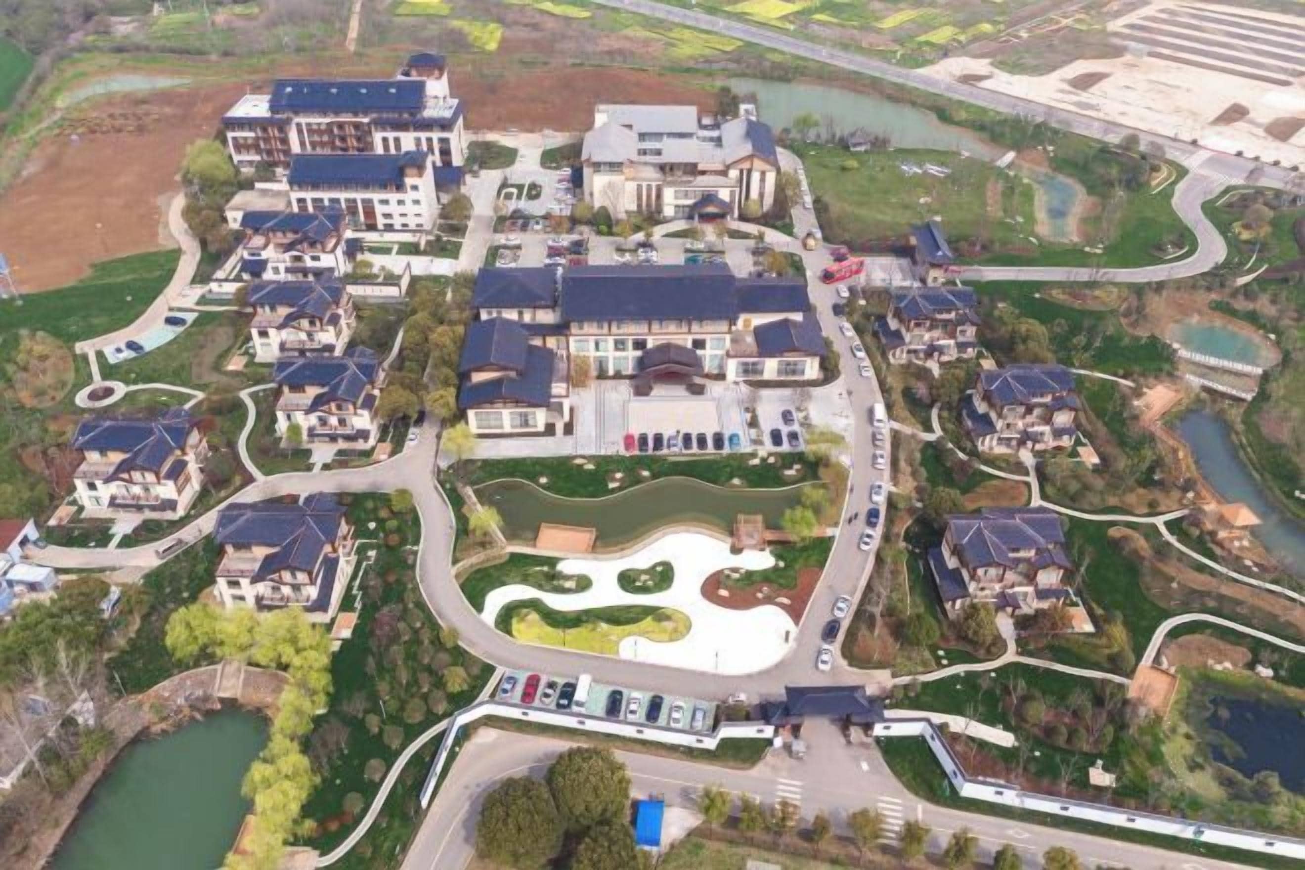 Zona residencial con varias casas, un área ajardinada central y una masa de agua.