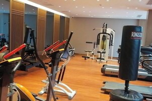 Un gimnasio con equipo de ejercicio, incluyendo cintas de correr y un saco de boxeo.