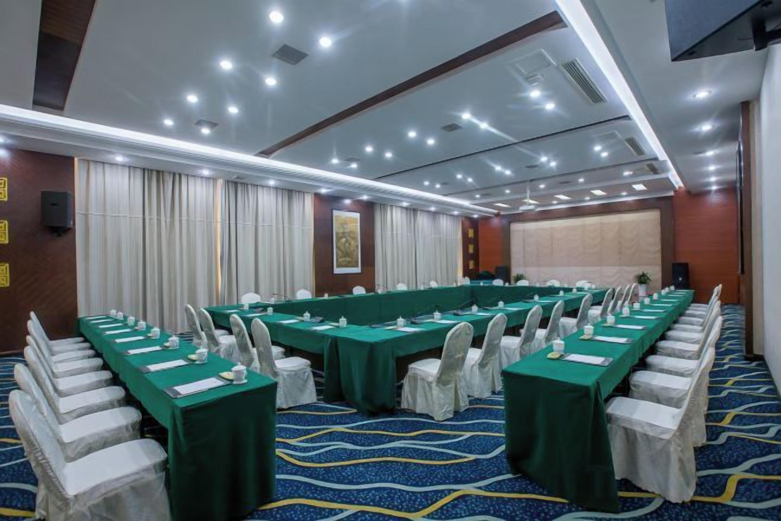 A conference room with long tables, chairs, and a carpeted floor.