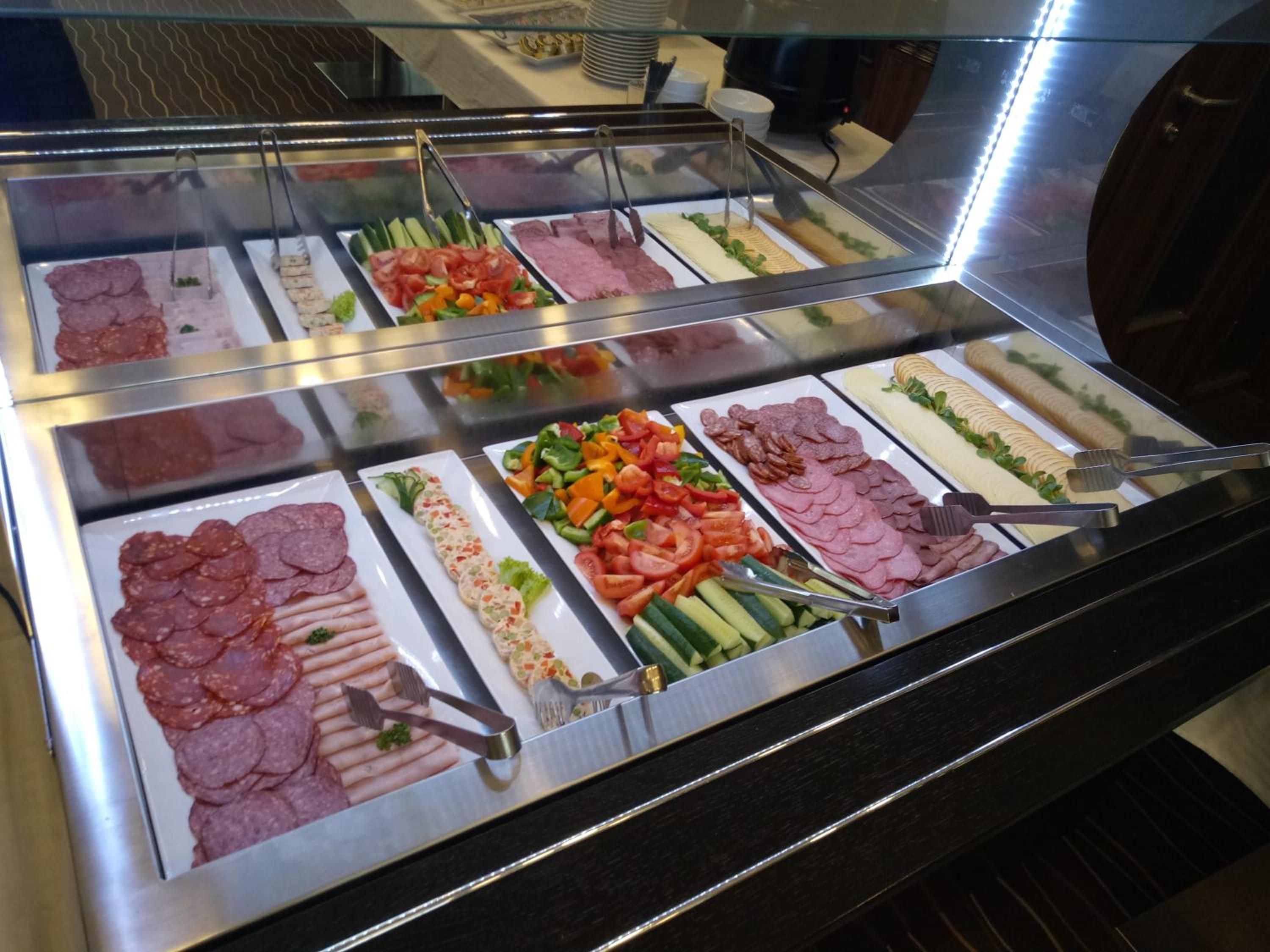 A buffet with various food options including meats, vegetables, and salads.