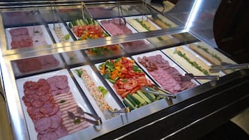 Ein Buffet mit verschiedenen Speisen, darunter Fleisch, Gemüse und Salate.