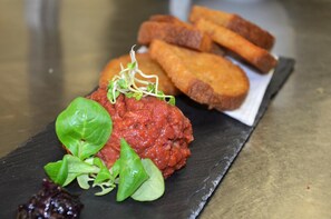A dish with a red sauce, green leaves, and a dark plate.