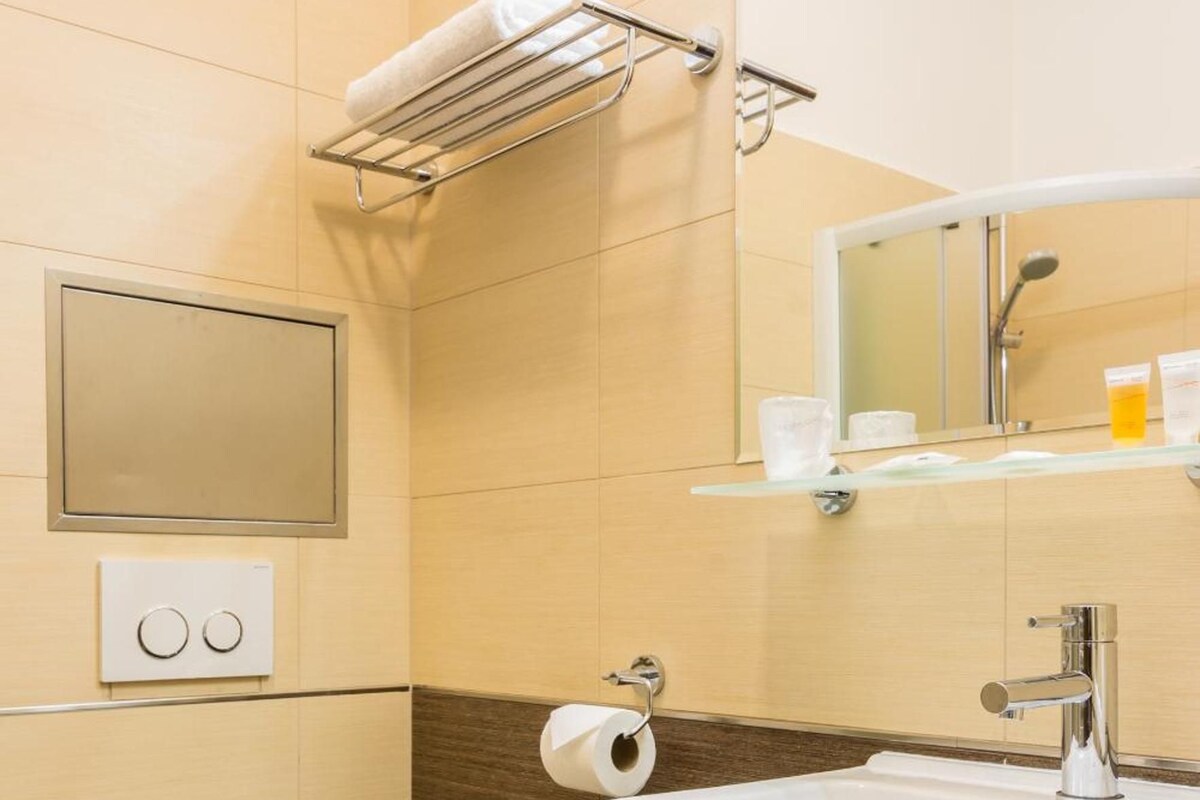 Une salle de bain moderne équipée de toilettes, d’un lavabo, d’un miroir et d’un porte-serviettes.