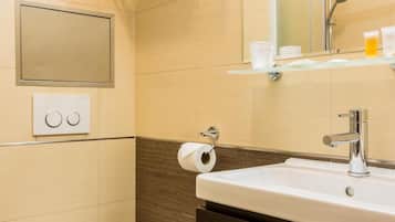 Ein modernes Badezimmer mit Toilette, Waschbecken, Spiegel und Handtuchhalter.