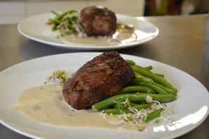 A plate with a steak and green beans, and a creamy sauce.