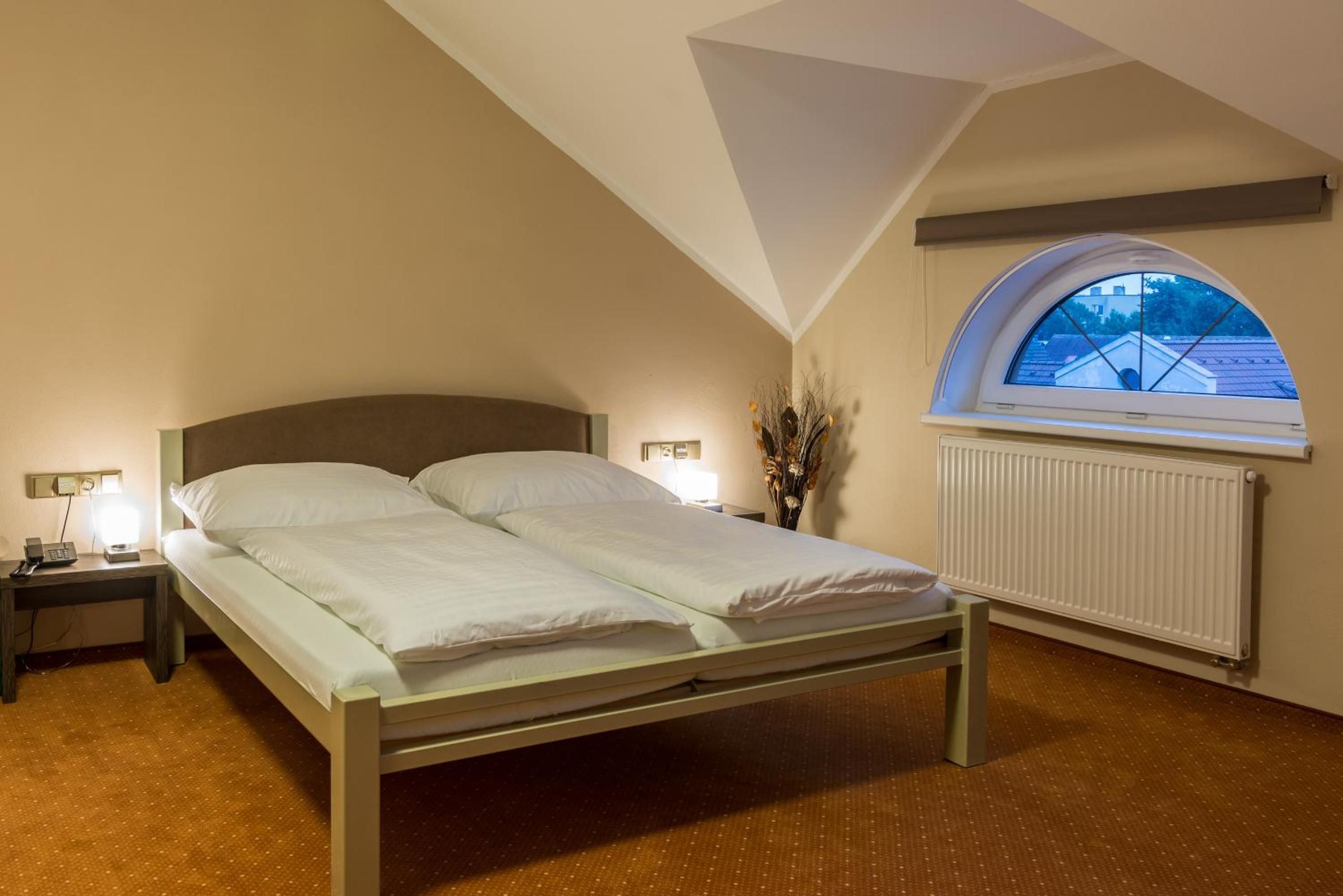 Un dormitorio con cama, lámparas de noche, un radiador y un tragaluz.