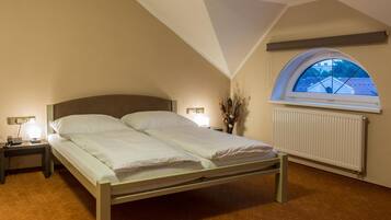 A bedroom with a bed, bedside lamps, a radiator, and a skylight.
