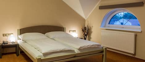 Un dormitorio con cama, lámparas de noche, un radiador y un tragaluz.