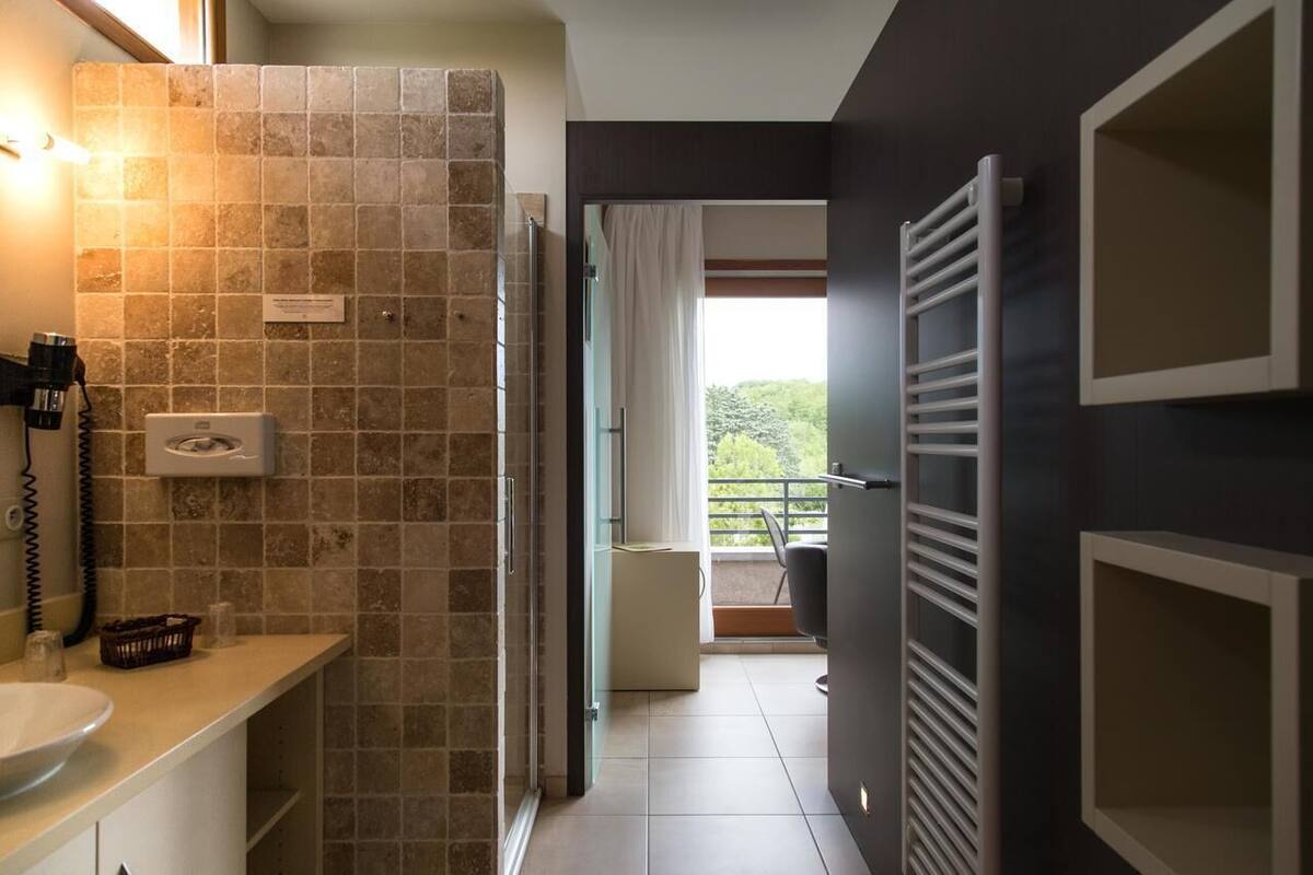 Une salle de bain avec un mur carrelé, un lavabo, un porte-serviettes et un espace douche.