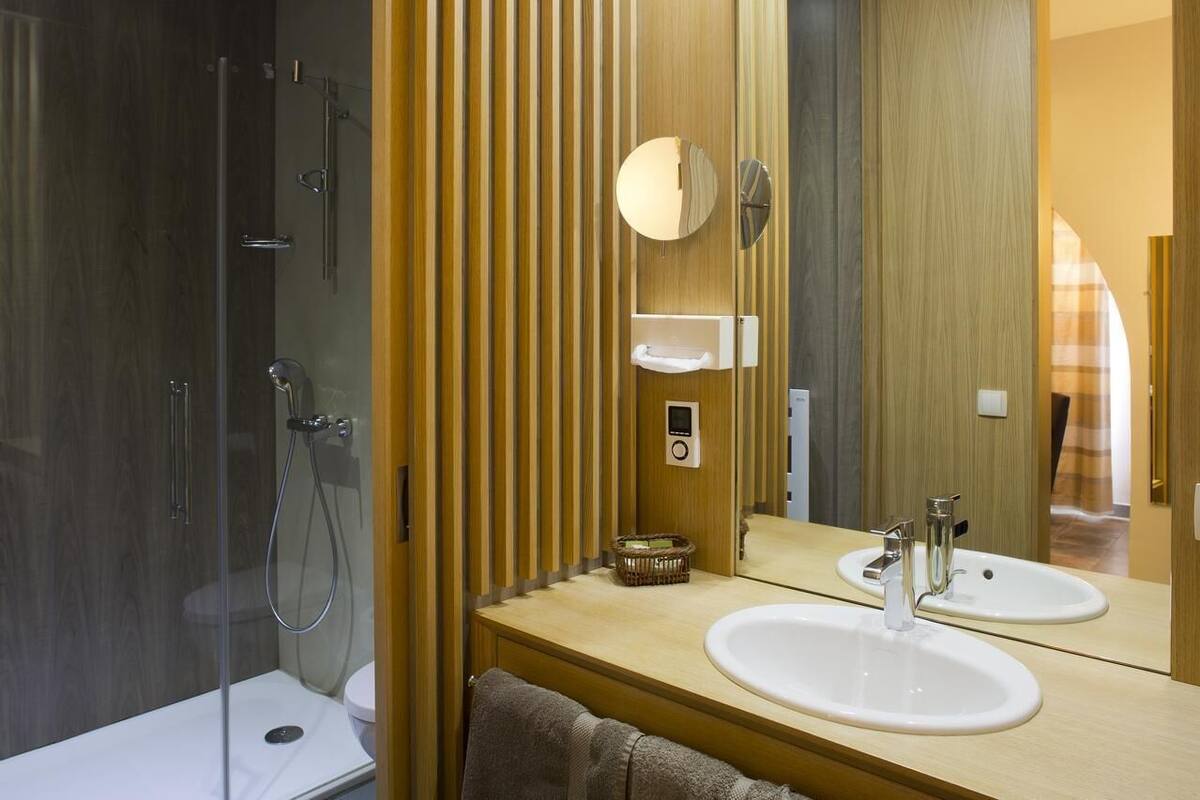 Une salle de bain moderne avec une douche à parois de verre, un meuble-lavabo en bois et un miroir.