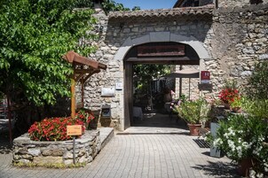 Uma entrada de restaurante em arco de pedra, com uma placa indicando que é um restaurante.