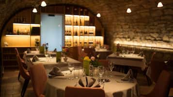 Een restaurant met gedekte tafels, een stenen muur en een bar met flessen.
