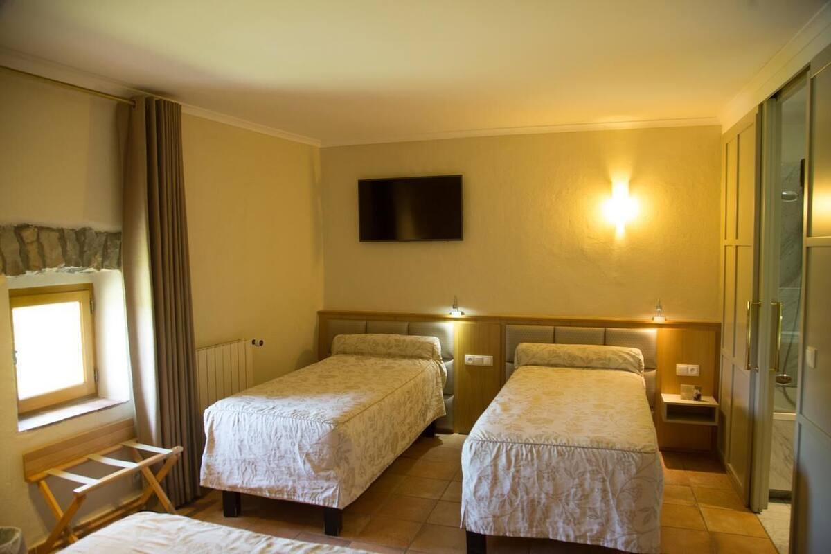 Une chambre d’hôtel avec deux lits, une télévision, une fenêtre avec des rideaux et une armoire.