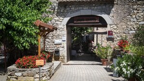 A stone archway entrance to a restaurant with a sign indicating it is a restaurant. - Logis Auberge les Murets (Chandolas)