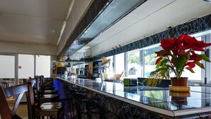 Zona de bar con mostrador de mármol, sillas de madera y un ventanal con vistas.