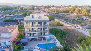 Un hotel de varios pisos con piscina, balcones y vistas del entorno.