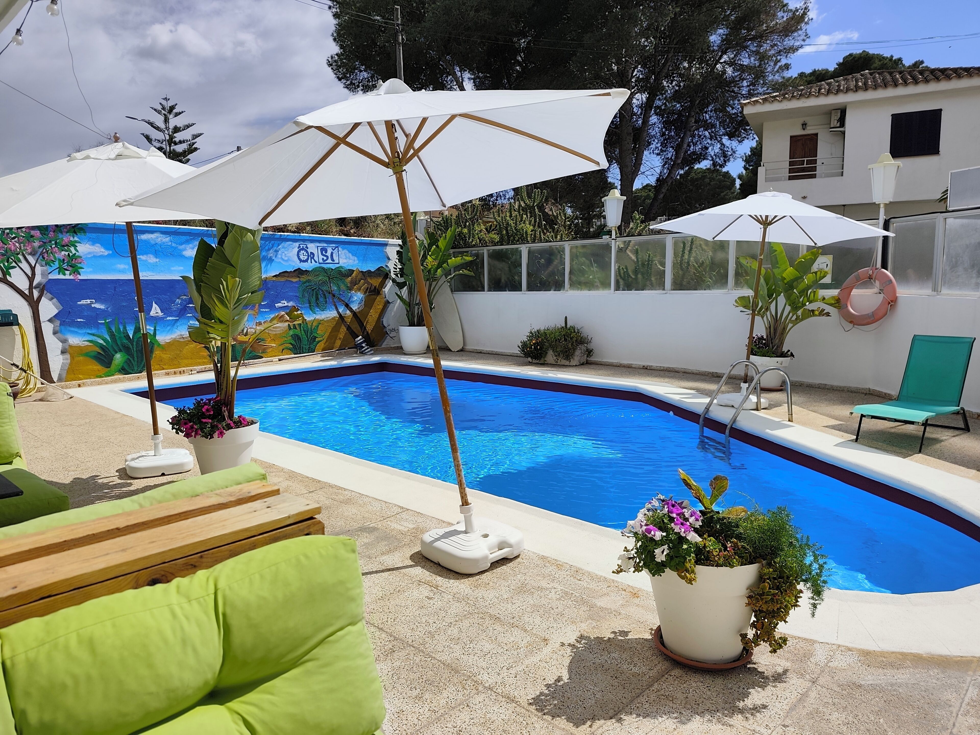 Piscina com mural, área de estar ao ar livre e guarda-sóis.