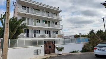 Un edificio de varios pisos con balcones, una entrada con reja y un cartel que indica que es un albergue.