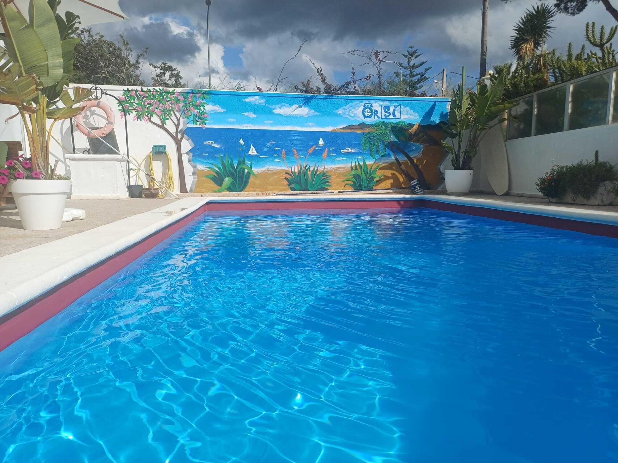 A swimming pool with a mural of a beach scene, including palm trees and a sailboat.