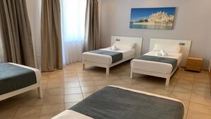 A hotel room with two single beds, a larger bed, and a small table. - Xapala (MALLORCA)