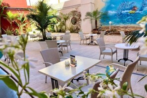 An outdoor patio with wicker furniture, a mural of a beach scene, and tropical plants. - Xapala (MALLORCA)