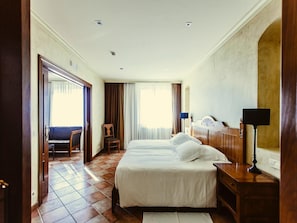 Habitación de hotel con una cama grande, un escritorio, una silla y vistas al exterior.