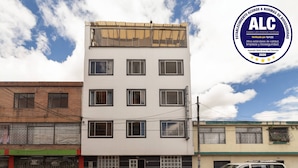 A multi-story building with a white facade, multiple windows, and a sign indicating it is a hotel. - Hotel Dorado 100 (Bogotá)