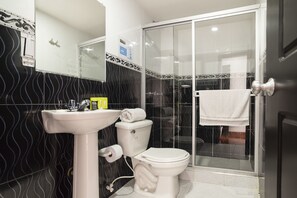 Een badkamer met een wit wastafelmeubel, toilet en douchecabine van glas.