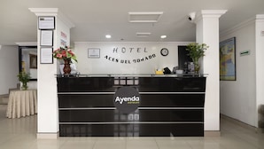 A hotel reception desk with a clock, framed certificates, and a map on the wall. - Hotel Dorado 100 (Bogotá)