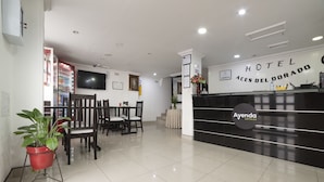 A hotel reception area with a modern design, including a reception desk, seating area, and a Coca-Cola vending machine. - Hotel Dorado 100 (Bogotá)
