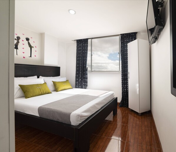Een keurig opgeruimde hotelkamer met een bed, een kledingkast, een raam met gordijnen en een decoratie aan de muur.