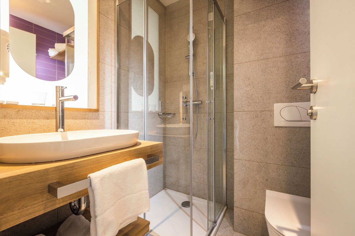 A modern bathroom with a glass shower enclosure, a wooden vanity with a sink, and a white toilet.