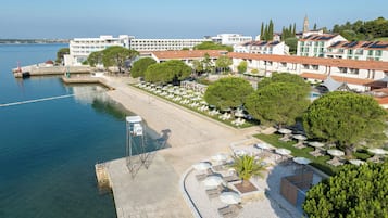 Un hotel frente al mar con un patio junto a la playa, piscina y vistas al océano.