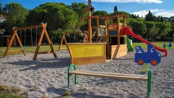 A playground with swings, a slide, and a sandbox labeled "Roh".