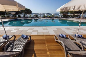 A poolside area with lounge chairs and umbrellas, a clear pool, and a view of the sea. - Hotel Vile Park Premium (Piran)