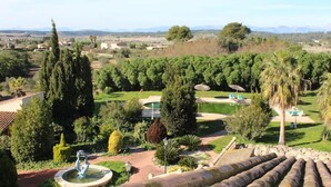 A landscaped garden with a fountain, palm trees, and a pool area. - SON Manera Hotel Rural (MALLORCA)