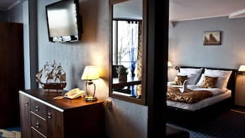 A hotel room with a bed, a dresser, a mirror, a television, and a window with curtains.