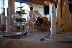 A table set for a meal with a fruit bowl, wine glasses, and a tiered dessert stand. - Shuma (Dabrowa Gornicza)