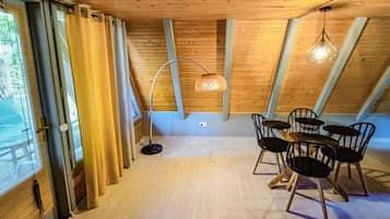 A room with a wooden ceiling, a dining table with chairs, and a hanging light fixture.