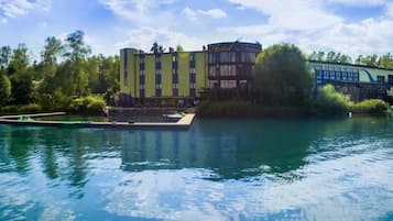 A hotel with a pool, surrounded by trees, and a dock with boats.