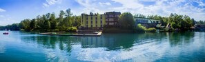 A hotel with a pool, surrounded by trees, and a dock with boats.