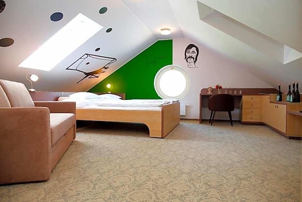 A bedroom with a bed, a desk, a chair, a wardrobe, a round mirror, and a skylight.