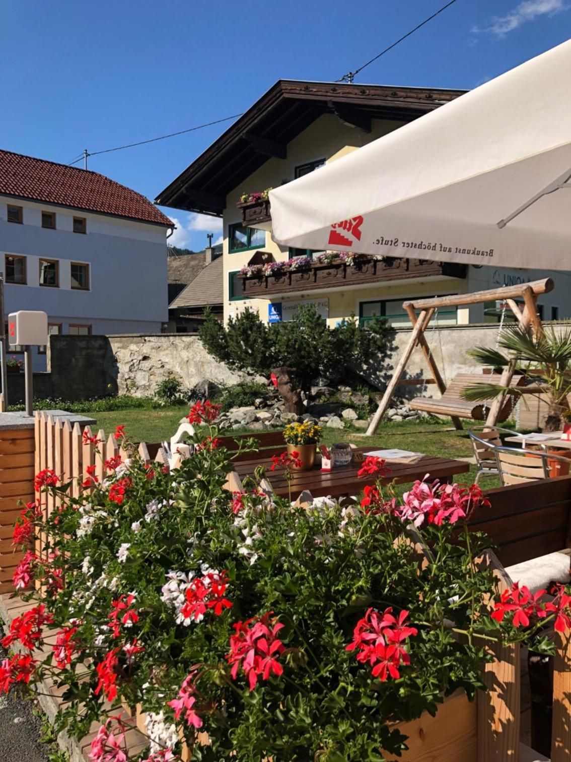 Ein Hotel mit weißer Fassade, Außenbereich und einem Garten mit roten Blumen.