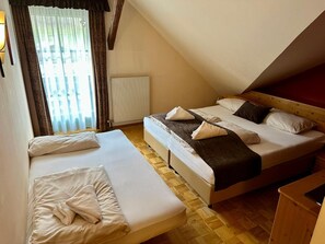 A room with two beds, a radiator, and a window with curtains.